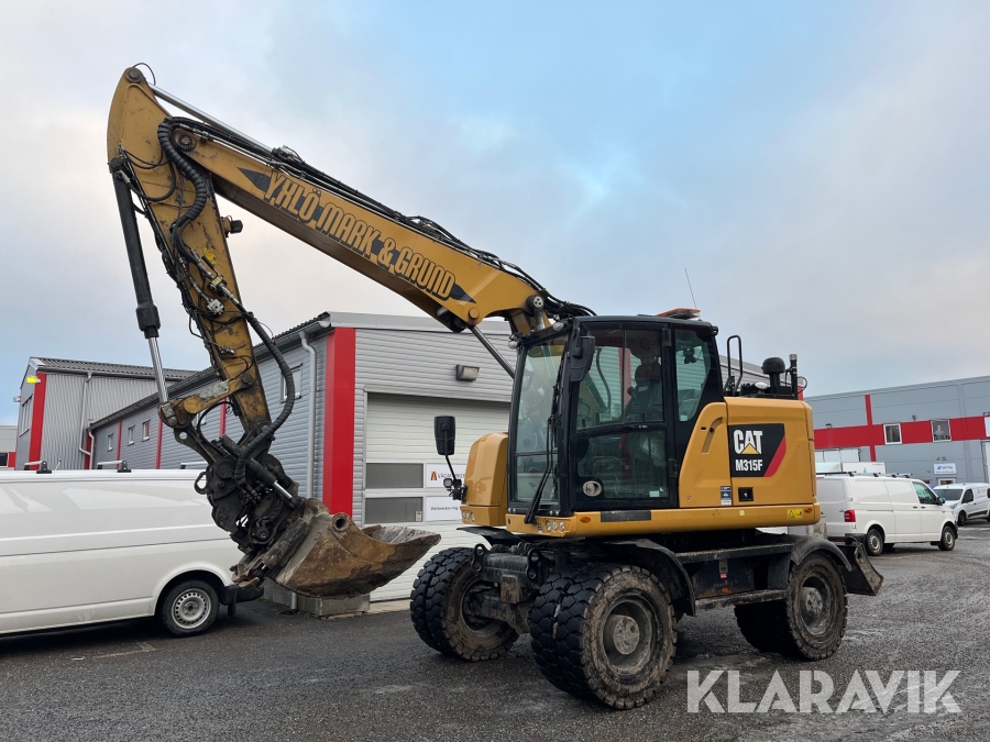 Grävmaskin CAT M315F med kärra och flera redskap