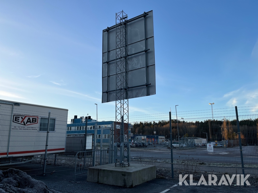 Fackverksmast med betongfundament och skylt